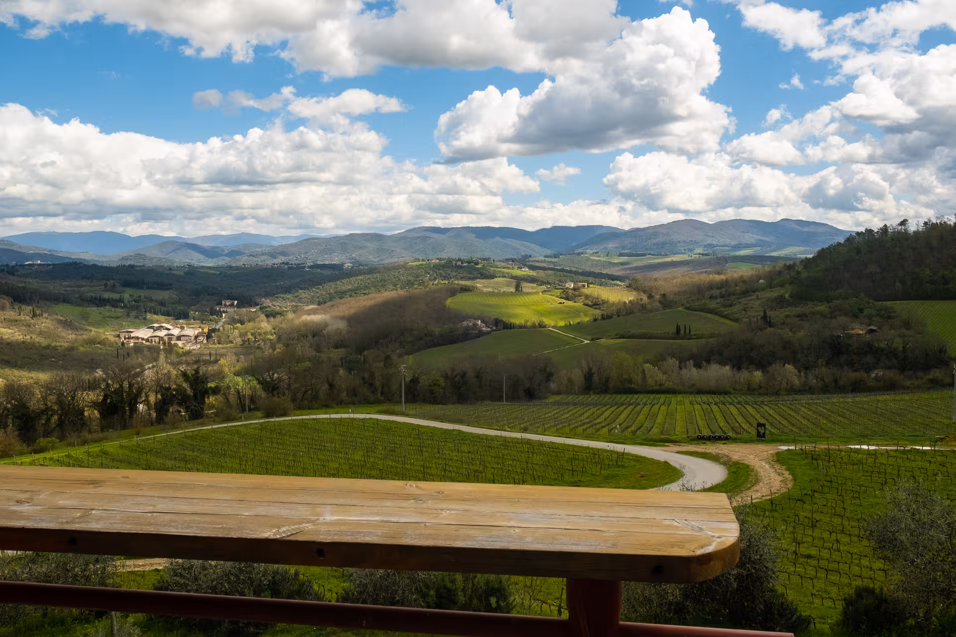 Scenic view of rolling Tuscan hills and vineyards under a blue sky, perfect for a vintage FIAT 500 tour.