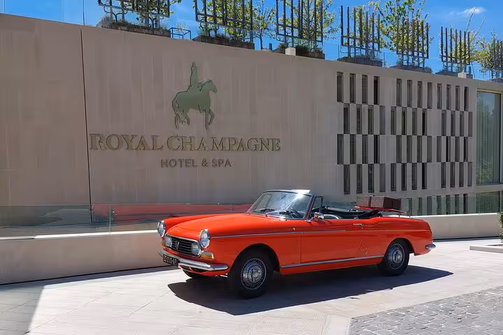 Red vintage convertible Peugeot parked outside Royal Champagne Hotel & Spa on a sunny day