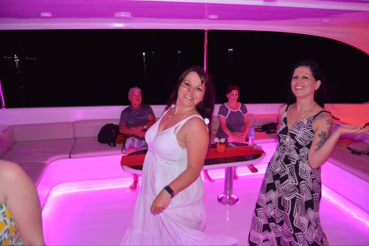 Guests dancing under pink lights on a VIP boat dinner cruise in Sharm El Sheikh, Red Sea nightlife experience