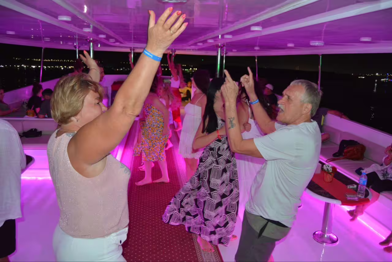 Guests dancing under purple lights on VIP boat night party during Sharm El Sheikh dinner cruise