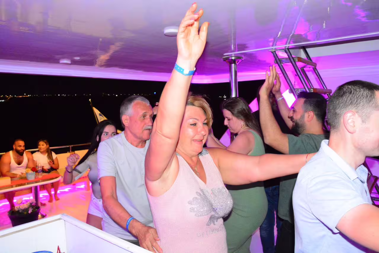 Guests dancing and clapping on VIP boat dinner cruise in Sharm El Sheikh, lively nightlife on the Red Sea