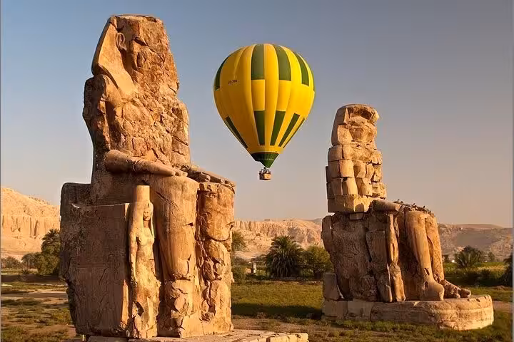 VIP Luxor hot air balloon tour floating near Colossi of Memnon at sunrise with pickup from all hotels