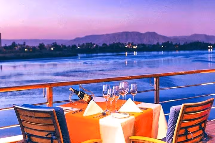 Romantic sunset dinner on Nile cruise deck with wine and river views on VIP 4 days Aswan to Luxor tour