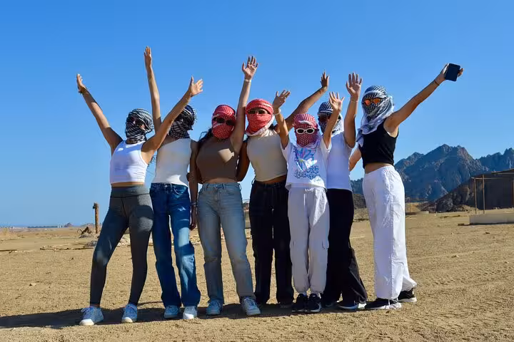 Group photo stop on private VIP quad bike adventure in Sharm El Sheikh desert, riders cheering with arms up