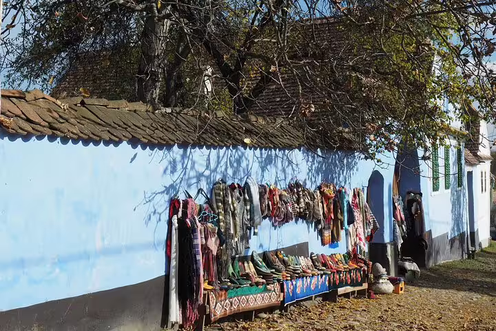 Colorful traditional clothing and textiles displayed along a blue wall in Viscri village, Transylvania