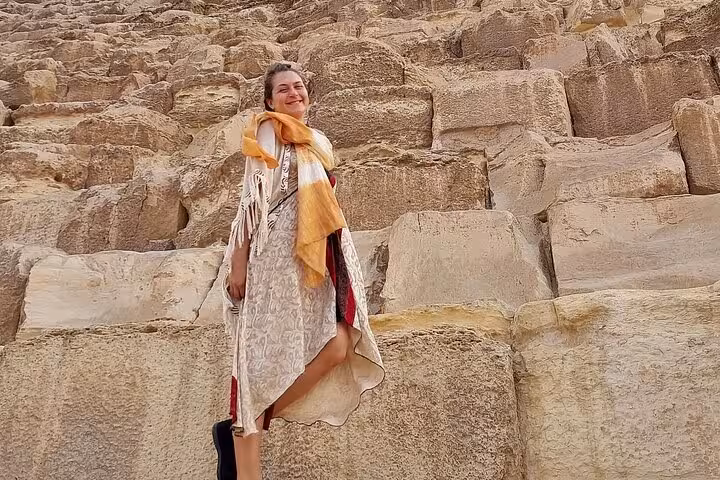 Visitor posing on massive limestone blocks of the Great Pyramid of Giza during Cairo private day trip