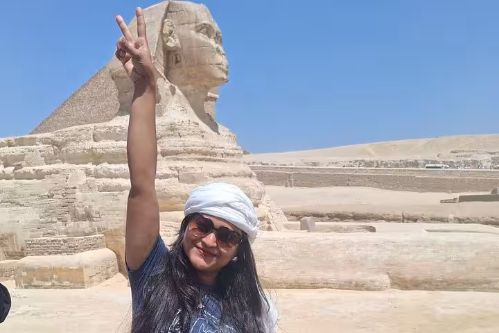 Visitor posing with the Great Sphinx in Egypt, enjoying a private tour of pyramids and local attractions.