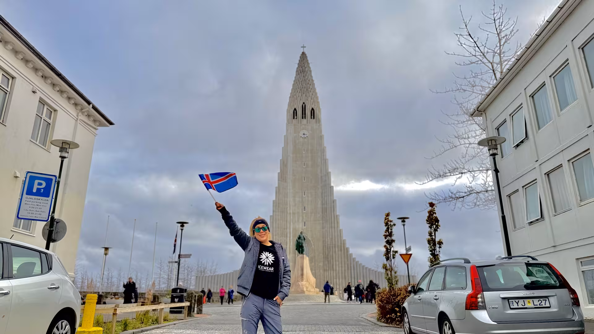 Visitor holding Iceland flag in front of Hallgrímskirkja church, Reykjavik, during Snæfellsnes Peninsula tour.