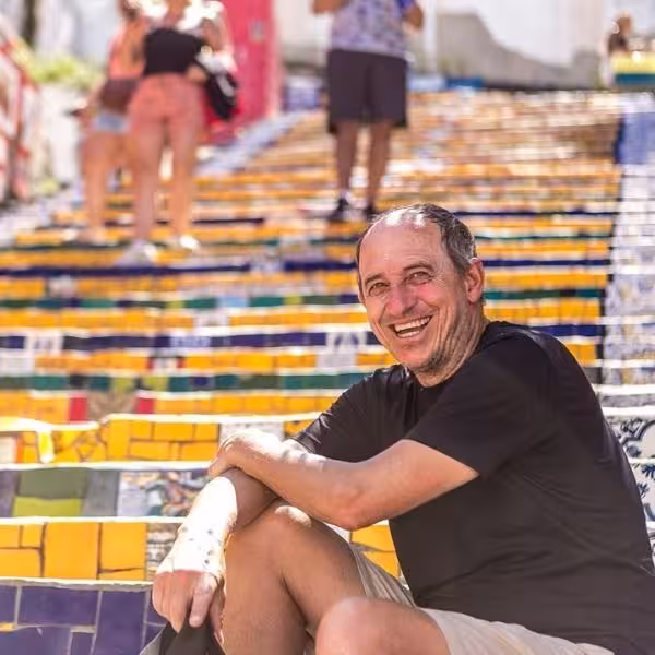 Smiling visitor sitting on vibrant Selarón Steps during private tour in Santa Teresa, Rio.