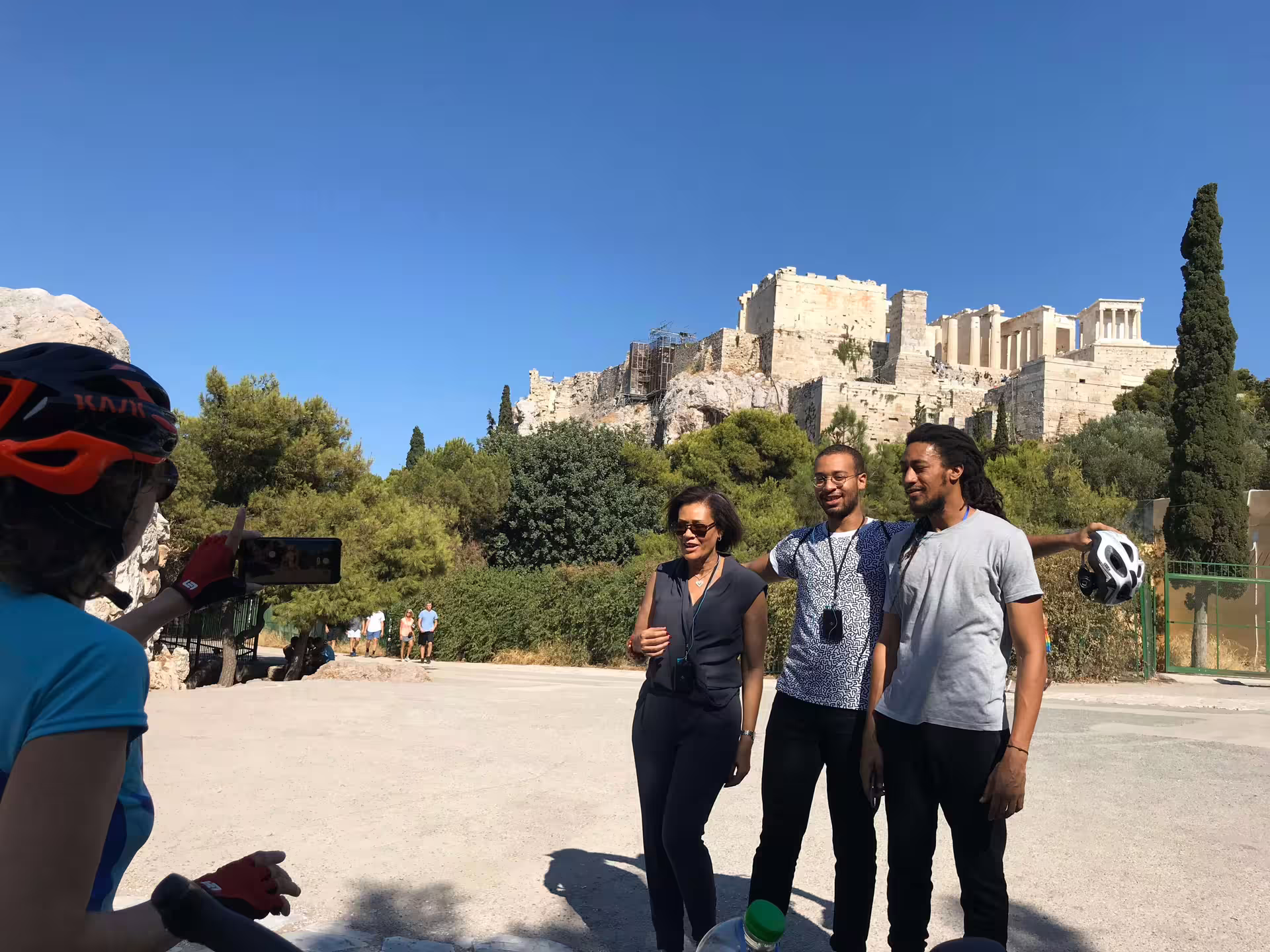Visitors posing for a photo with the iconic Acropolis in the background, capturing memories of Athens sightseeing.