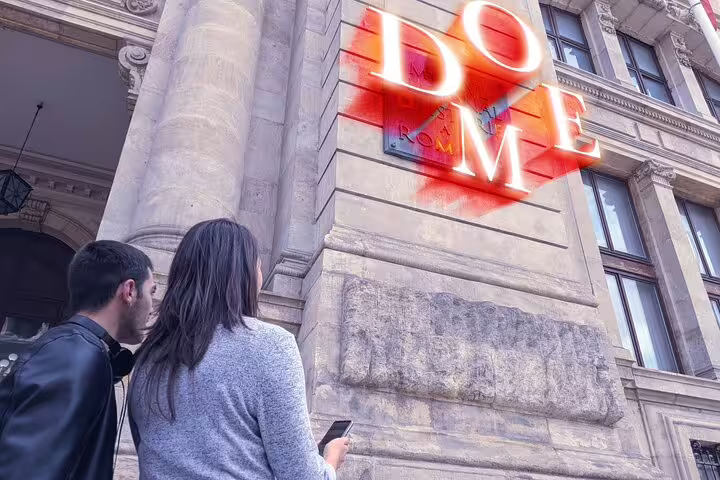 Two visitors looking up at glowing DOME sign on historic stone building facade