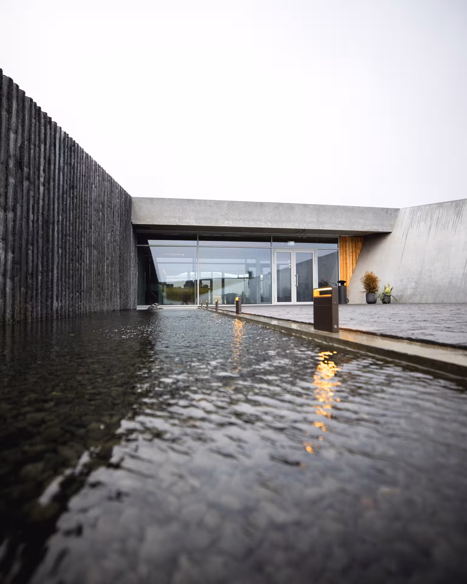 Modern concrete entrance of Vok Baths with reflective geothermal pool in East Iceland