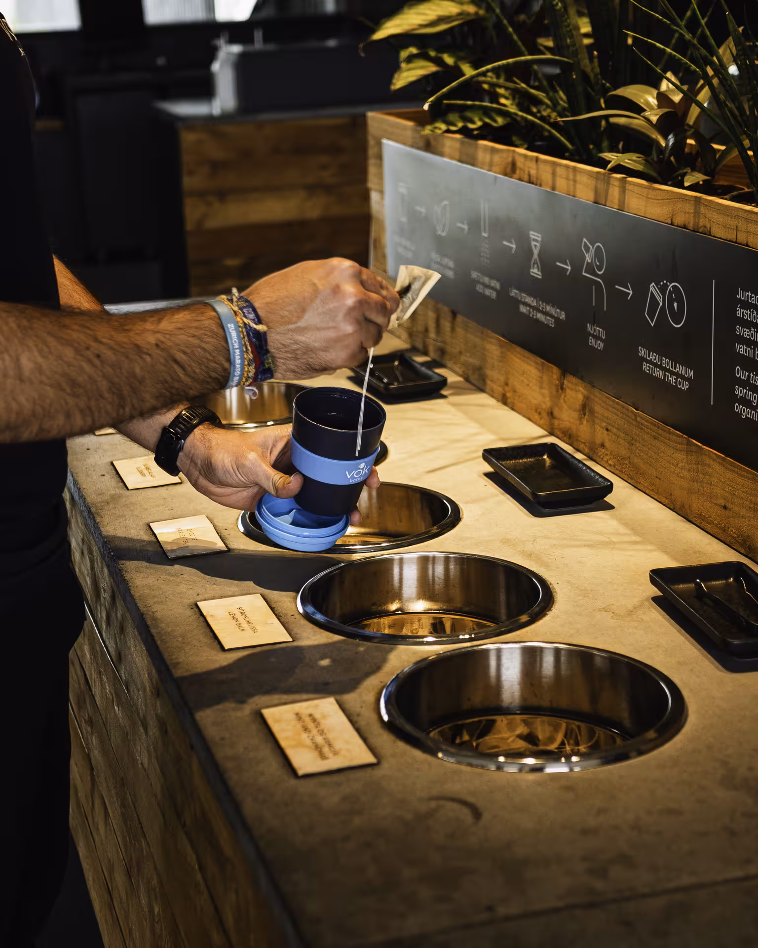 Person preparing herbal tea infusion at Vok Baths geothermal self-serve station in Iceland