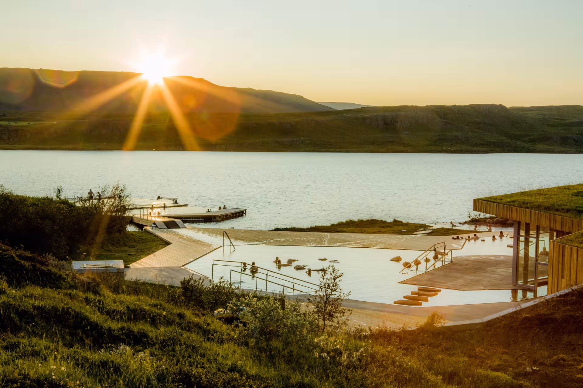 Vok Baths geothermal infinity pool at sunset beside a calm lake in East Iceland