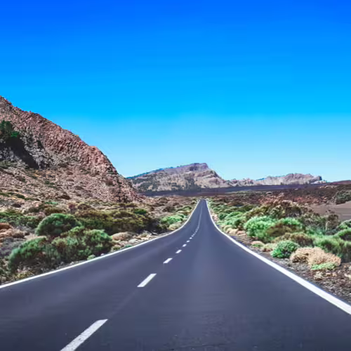 Scenic highway through volcanic landscape ideal for private cruise excursions in Tenerife, under a clear blue sky.