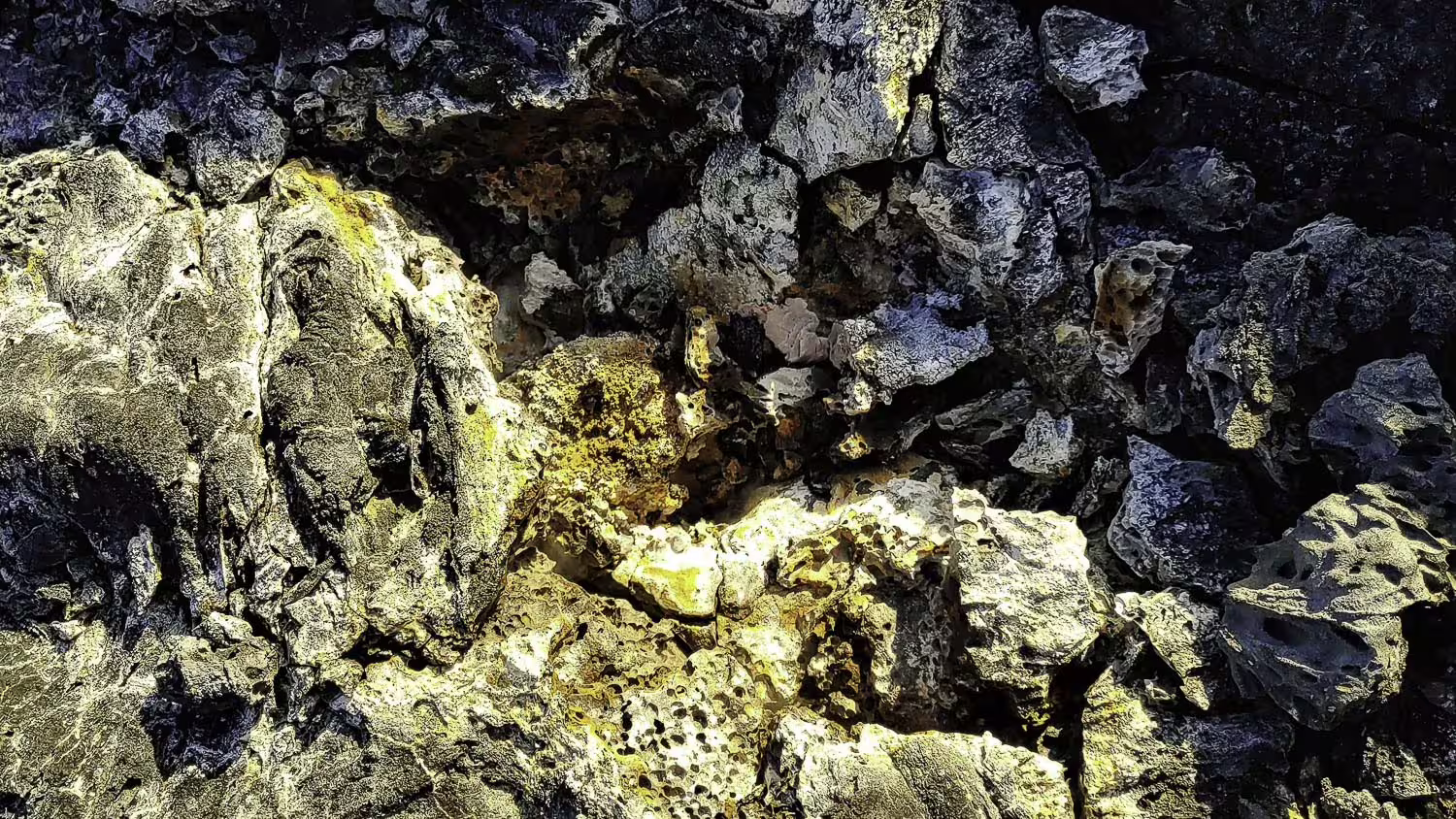 Rugged volcanic lava rock formations with yellow sulfur deposits near Reykjavik Iceland