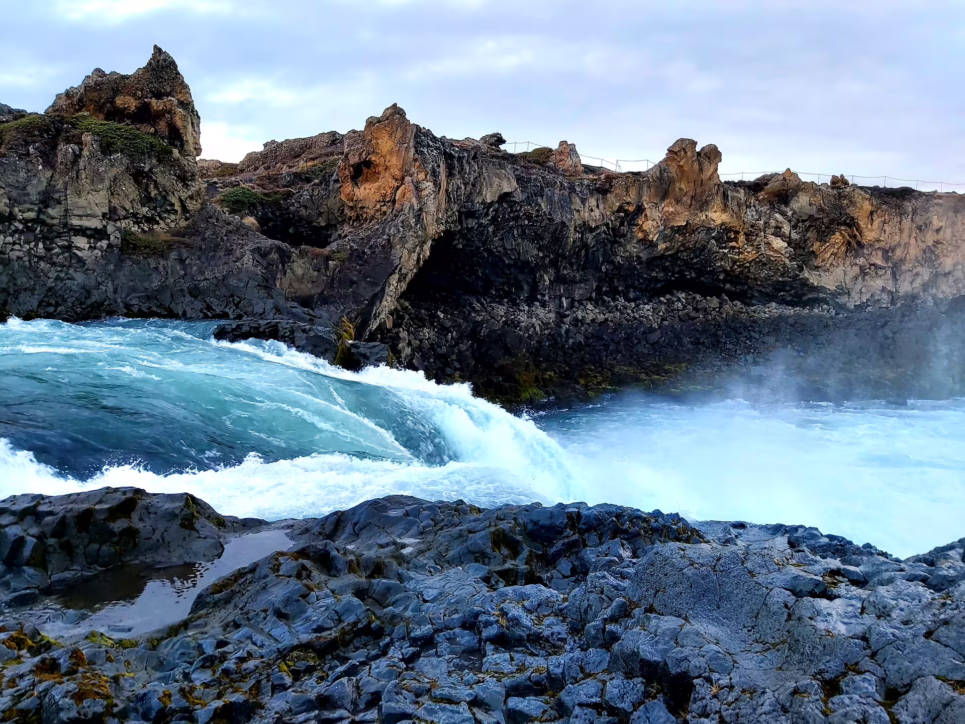 Powerful ocean waves crashing through volcanic basalt rock arch on Iceland's northern coastline