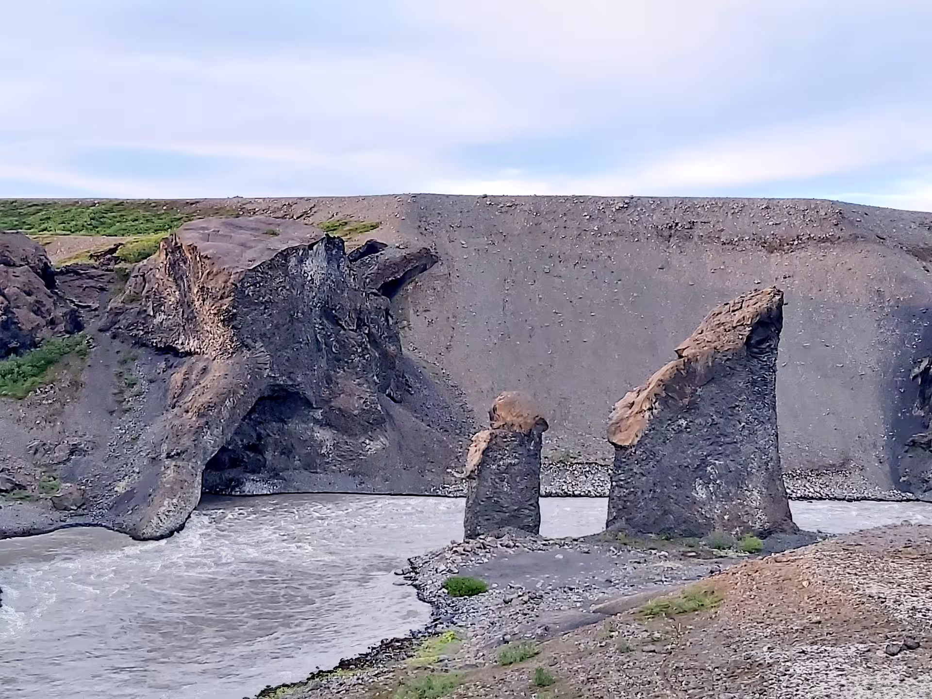 Dramatic volcanic rock formations and hoodoos along a glacial river in North Iceland