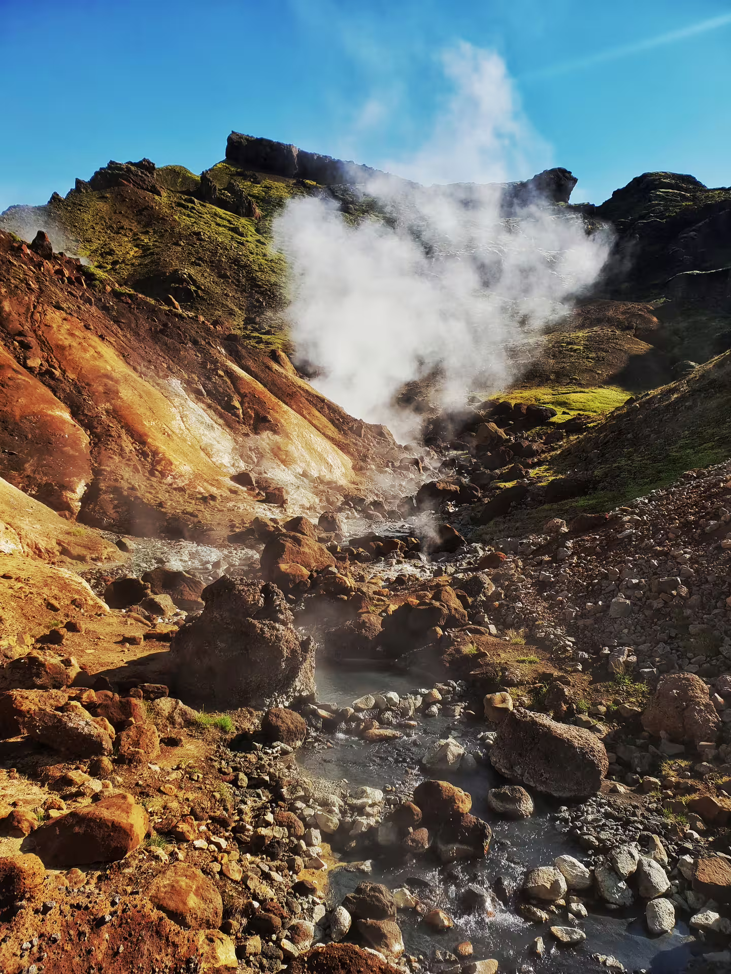 Steaming volcanic springs amid rocky terrain under a clear blue sky, perfect for an adventurous ATV tour experience.