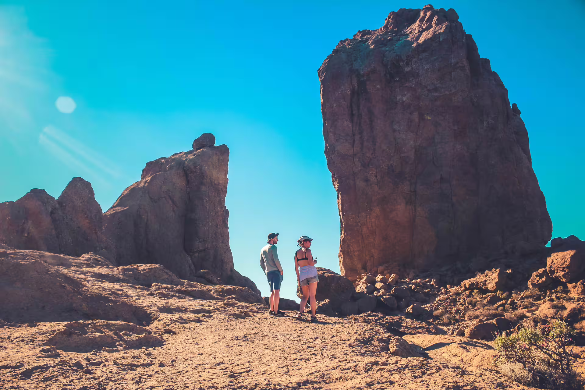 Two adventurers exploring massive volcanic rocks under a clear blue sky on the Volcano Heart Tour.
