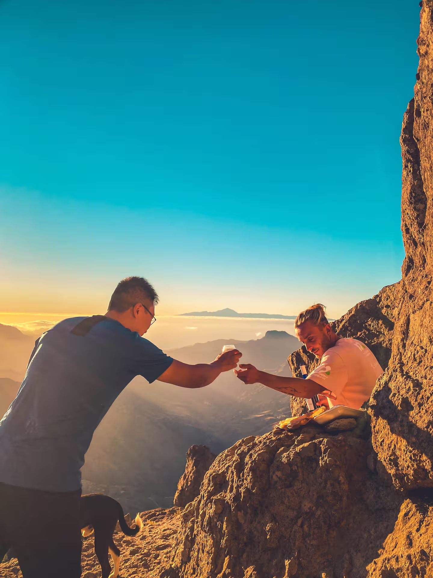 Two people toasting on a rocky peak at sunset during the Volcano Heart Tour, capturing a perfect adventure moment.