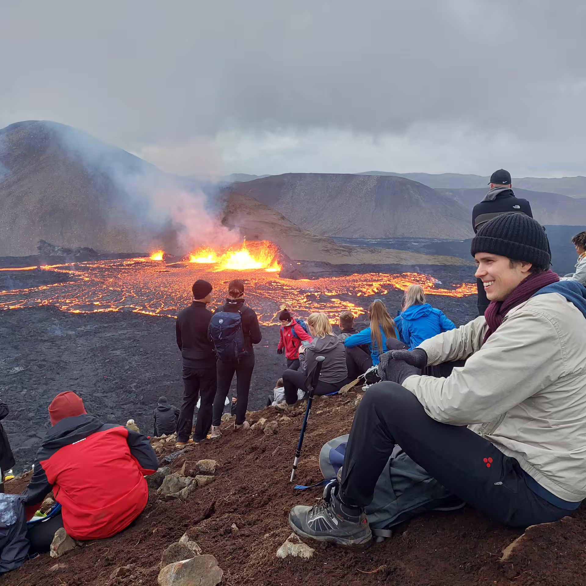 Tourists watching glowing lava flow from volcanic eruption on Iceland volcano hike near Reykjavik