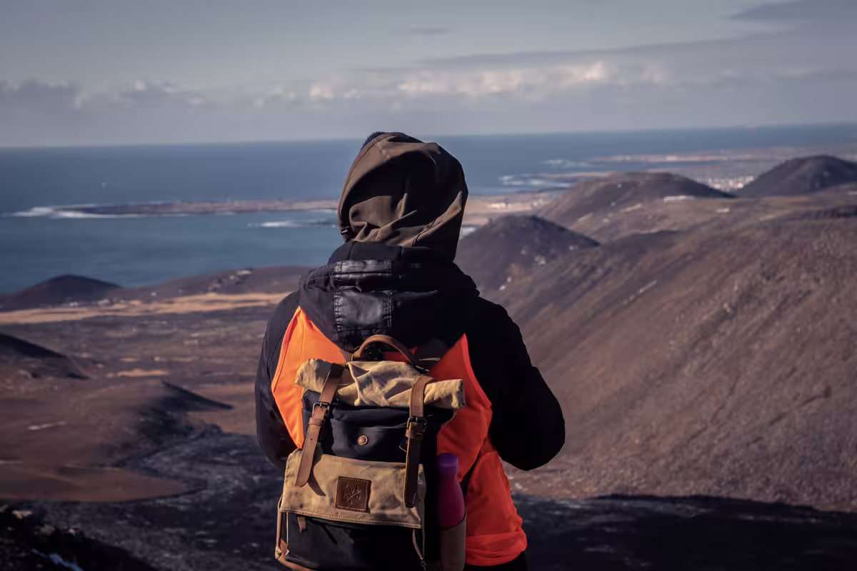 Hiker with backpack overlooking volcanic landscape and ocean from Reykjavik volcano summit