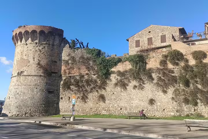 Ancient stone walls and tower of Volterra under blue skies, visited on a private Tuscany tour with lunch and wine tasting