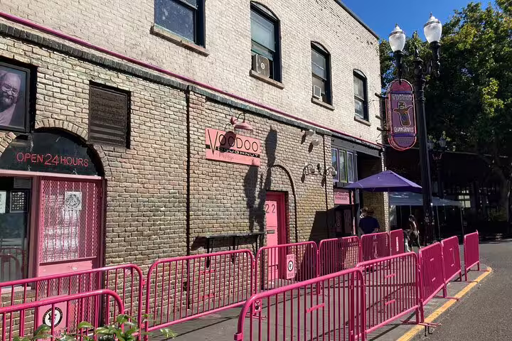 Voodoo Doughnut storefront with pink barriers and open 24 hours sign in Portland