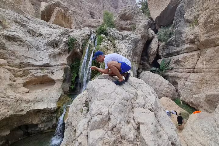 Visitor capturing the scenic beauty of Wadi Tiwi's cascading waterfalls on a private tour from Muscat.