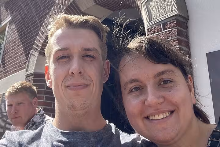 Two smiling adults posing for a selfie in front of a brick building in Delft