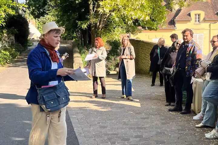 Tour guide leading a group of visitors on a walking tour along a cobblestone path in Auvers-sur-Oise