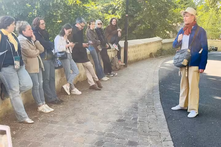 Tour guide addressing a group of visitors on a cobblestone path in Auvers-sur-Oise