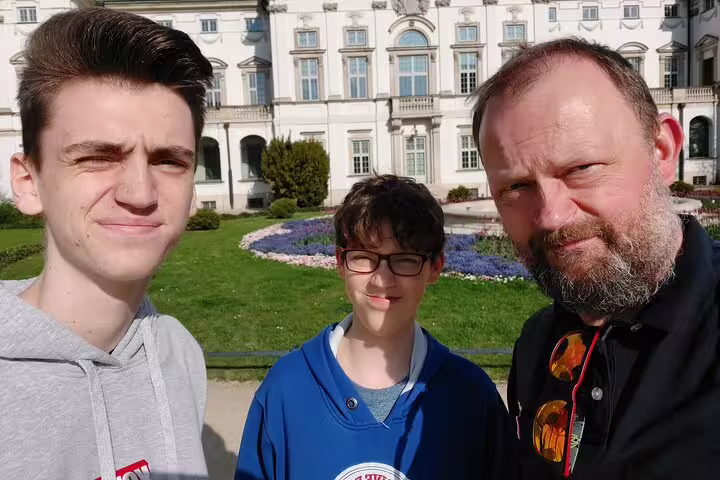 Three visitors posing in front of a grand white historic building in Warsaw
