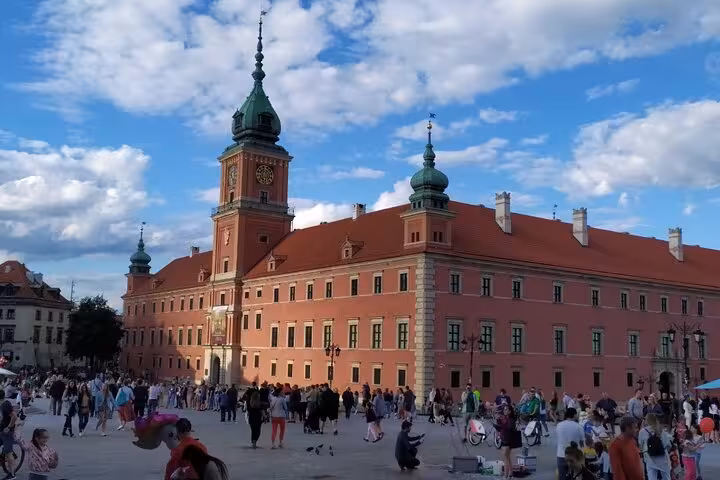 Crowds gather at Warsaw Royal Castle in Old Town square a key stop on a medieval Warsaw self-guided app tour
