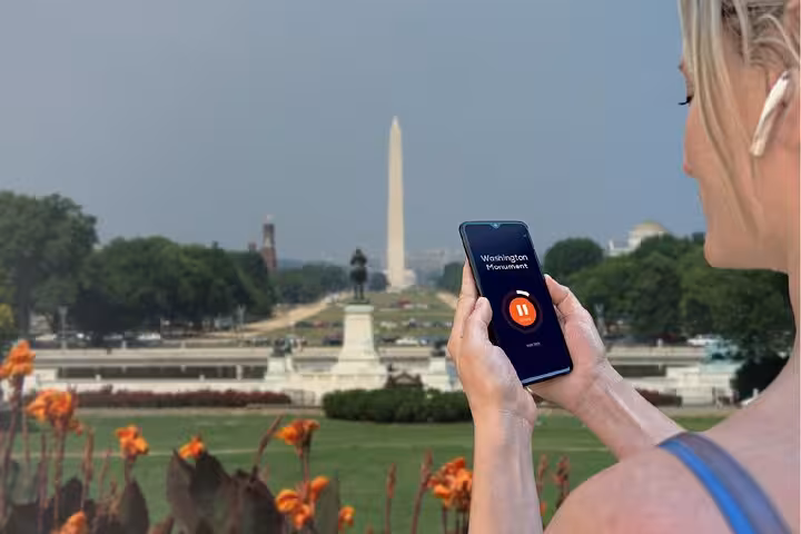 Woman holding smartphone with Washington Monument audio tour app on National Mall, Washington DC