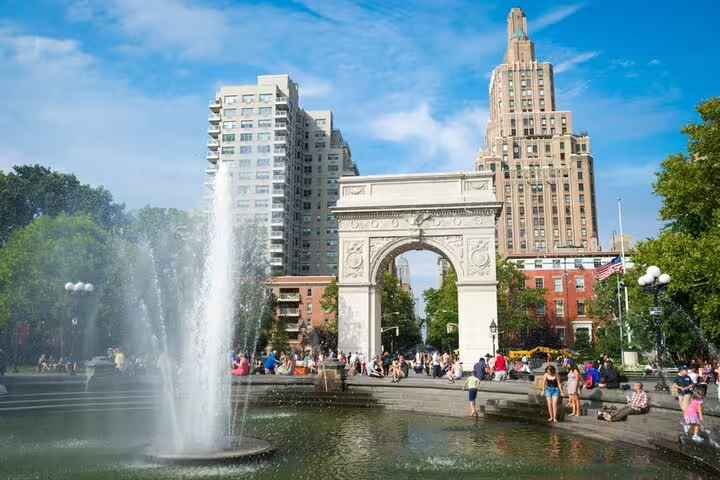 Washington Square Park fountain and arch with crowds on a sunny day in Greenwich Village, NYC
