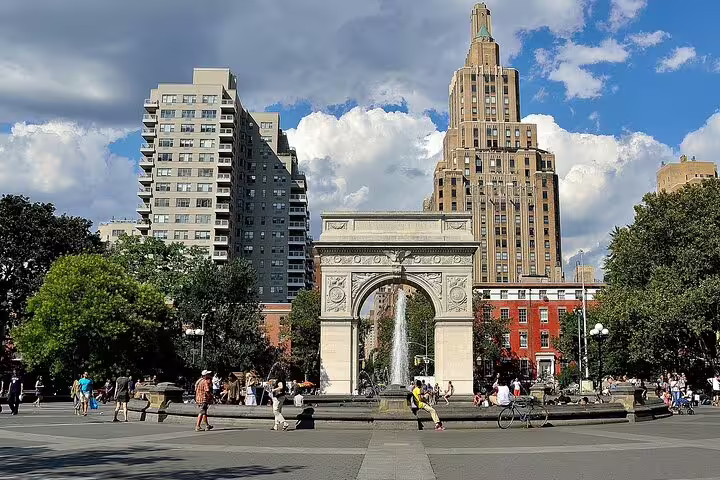Washington Square Park arch with fountain and Manhattan skyline on a sunny day