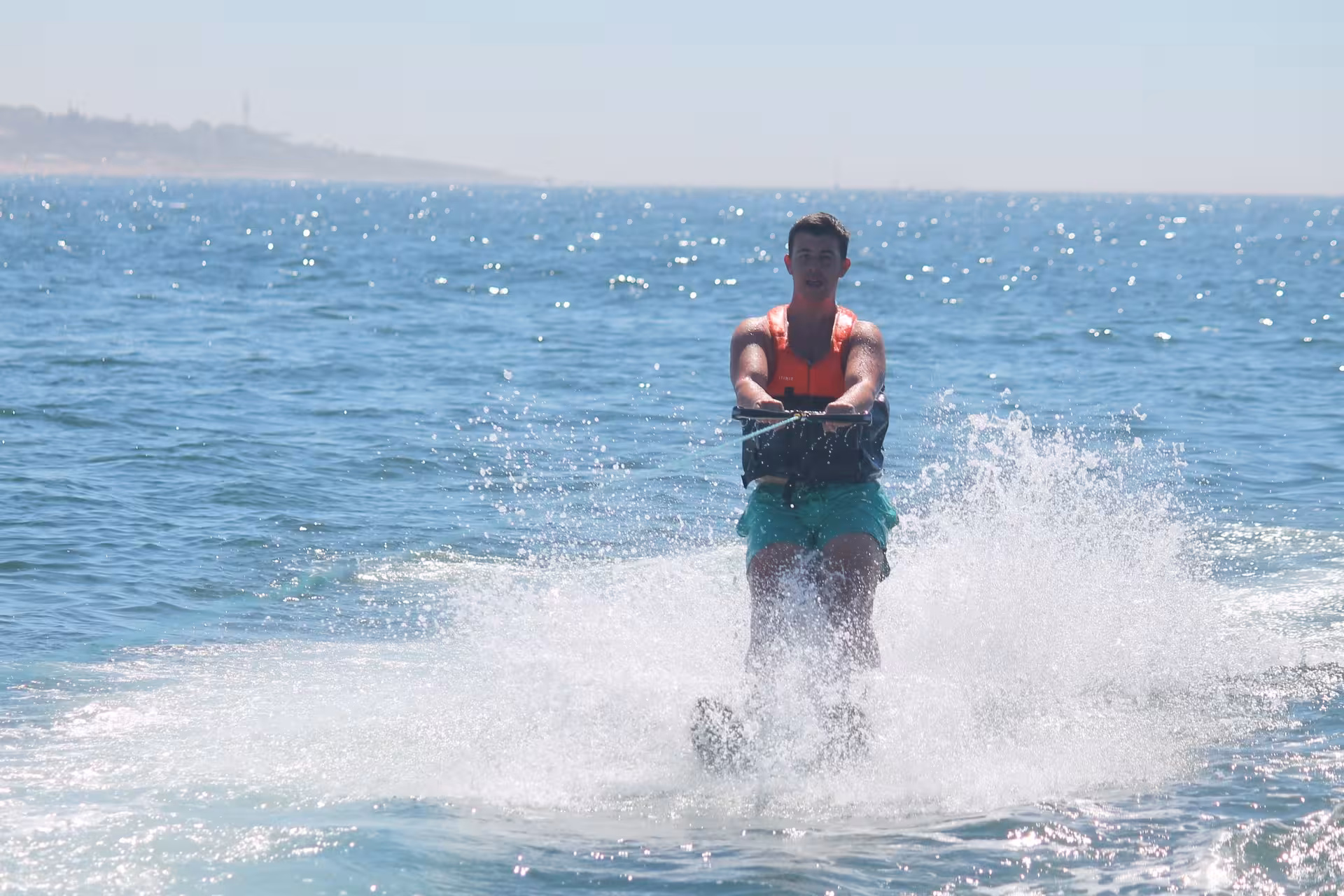 Smiling young man water skiing on sparkling blue ocean waters during an exciting Algarve water sports experience