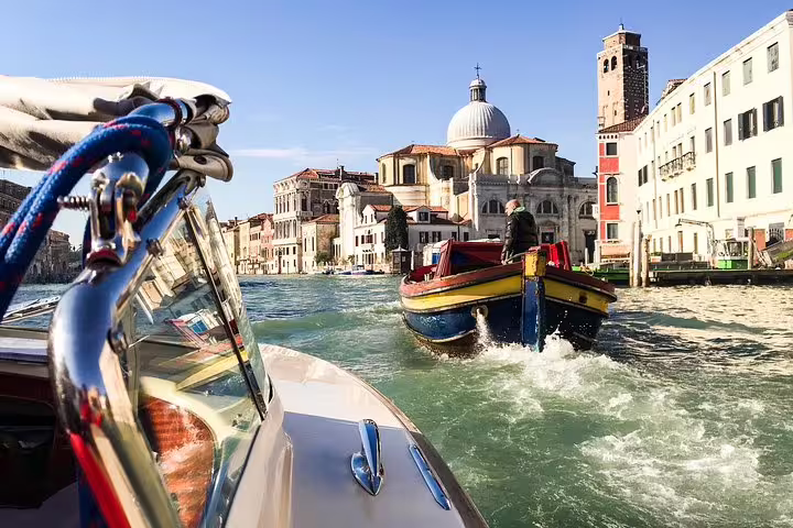 Scenic view from a water taxi navigating Venice's Grand Canal with iconic architecture in the background.