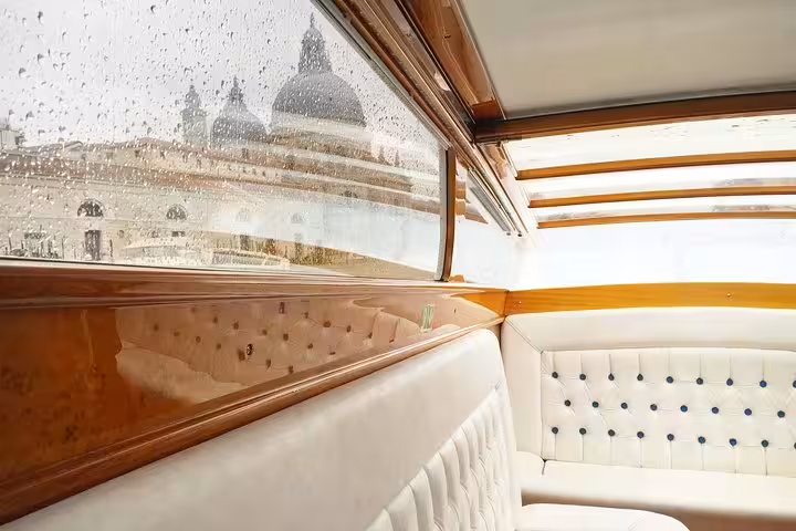 Cozy water taxi interior with Venice landmarks visible, ensuring a stylish transfer to VCE airport.
