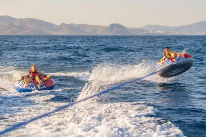 Two riders on inflatable tubes being towed by a speedboat on the French Riviera near Antibes