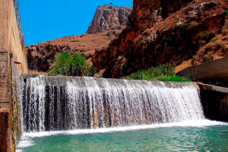 Small waterfall and turquoise pool in South Rethymno, Crete, framed by rugged gorge cliffs on nature day trip