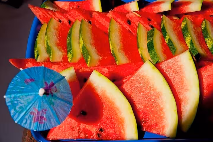 Fresh watermelon slices with decorative umbrella on board a Paraty boat tour, offering a refreshing tropical treat.