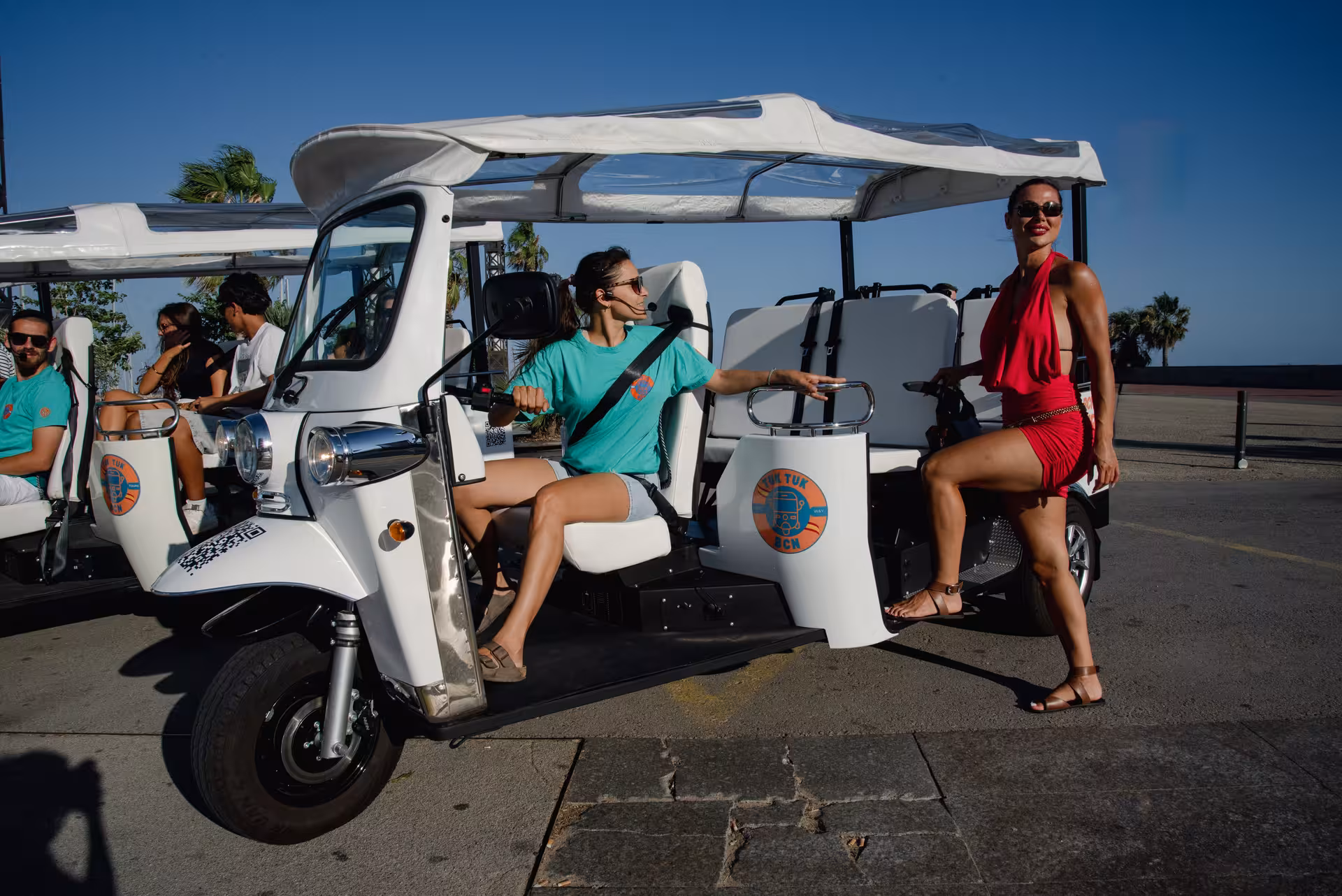 Welcome Tour Barcelona by electric tuk tuk, with guide and guests boarding near the seafront promenade