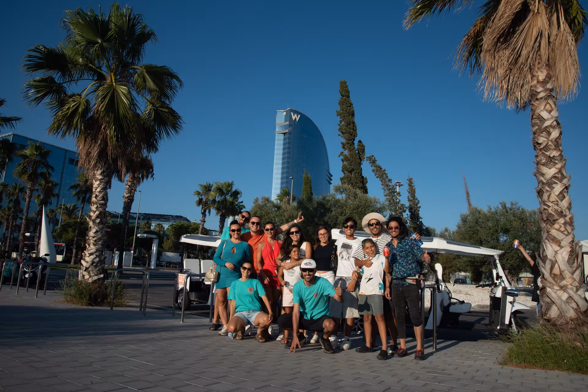 Group photo with guides on Welcome Tour Barcelona near W Barcelona Hotel, palm trees and tuk-tuk city tour