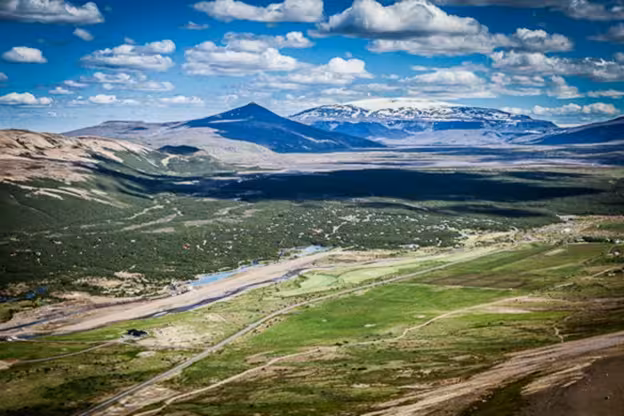 Aerial view of a green glacier valley with mountains and snow-capped peaks in West Iceland