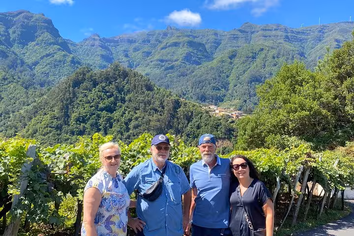 Tour group by lush vineyards with dramatic Madeira mountains, part of the West Madeira 4x4 expedition route