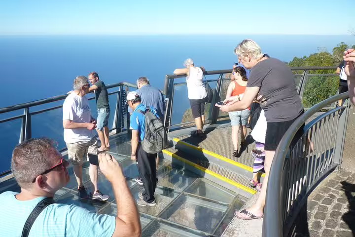 Tourists enjoy breathtaking ocean views from a glass-floored skywalk on the West Tour, perfect for thrill-seekers.