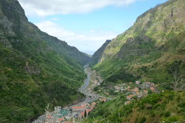 Scenic valley view with lush green hills and a winding river through a picturesque village on the West Tour.